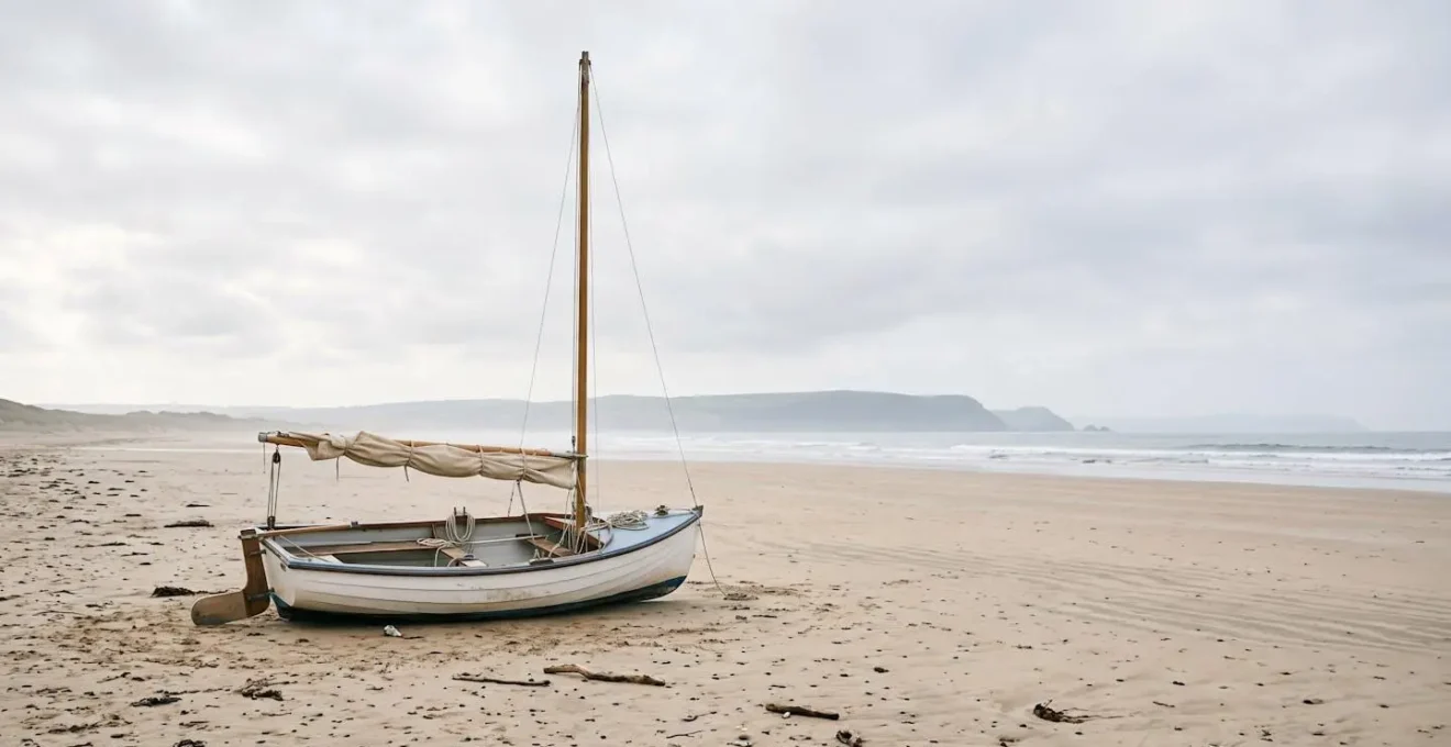 Petit voilier dériveur échoué sur une plage de sable lors d'une pause navigation