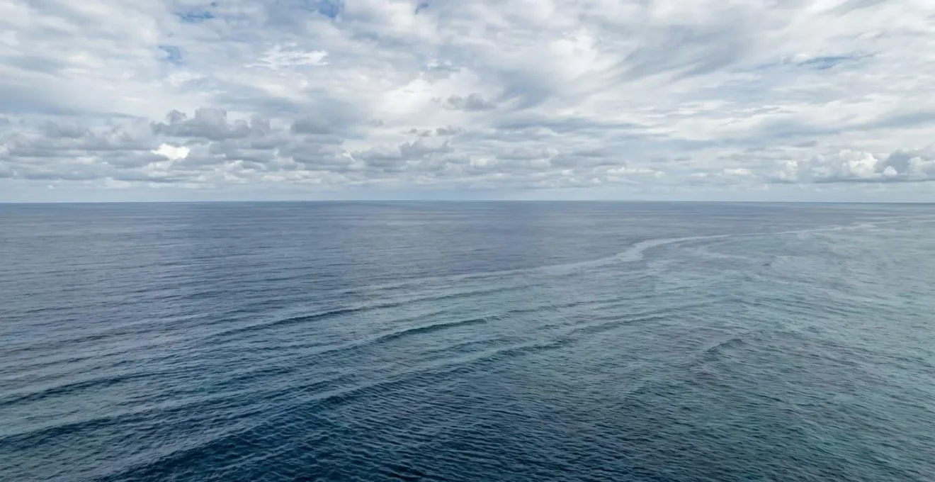 Vue aérienne minimaliste de l'océan Atlantique avec horizon infini et ciel nuageux évoquant les choix de routes océaniques