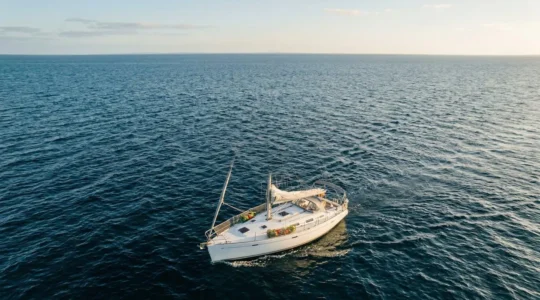 Vue aérienne d'un voilier hauturier en navigation avec filets de stockage suspendus à l'extérieur et espace de vie organisé
